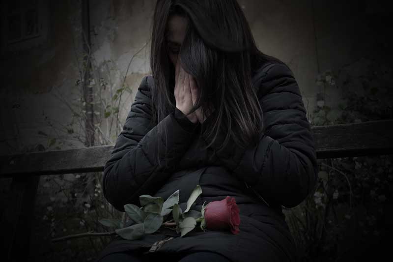 Mujer llorando con flor, por cibervenganza al hacer sexting