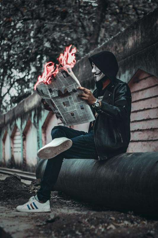 Hacker preparando ataque cibernético con periódico en llamas